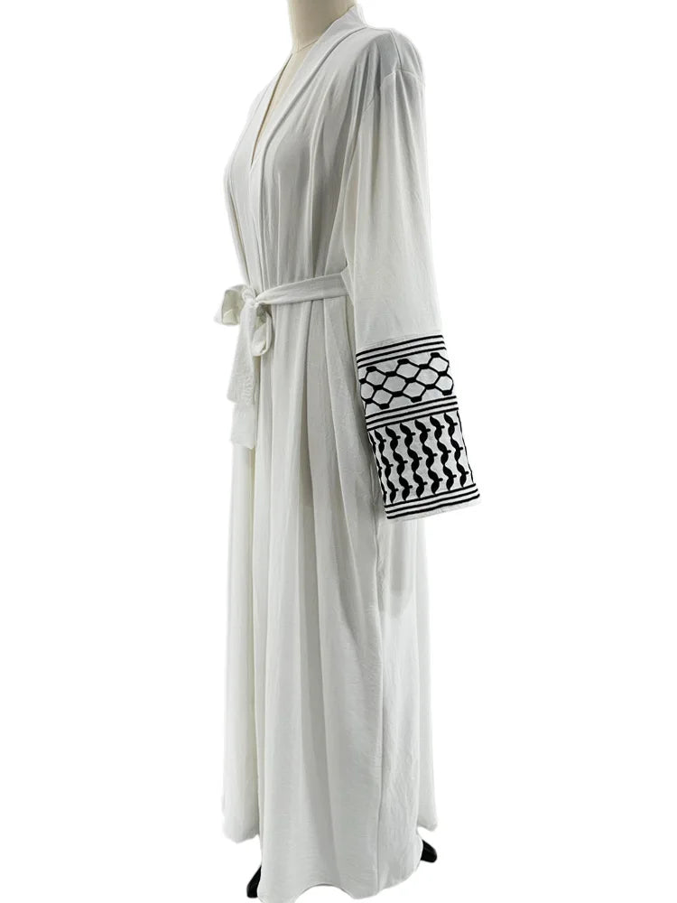 Kuffiyeh-inspired abaya with embroidered sleeves and detachable belt.