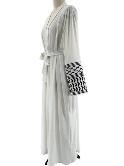 Kuffiyeh-inspired abaya with embroidered sleeves and detachable belt.